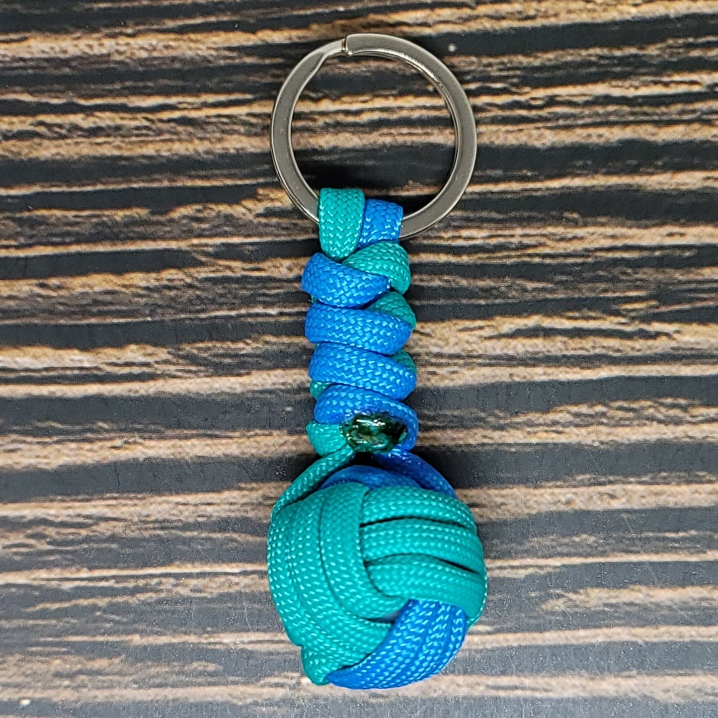 a blue and green knoted keychain on a wooden surface