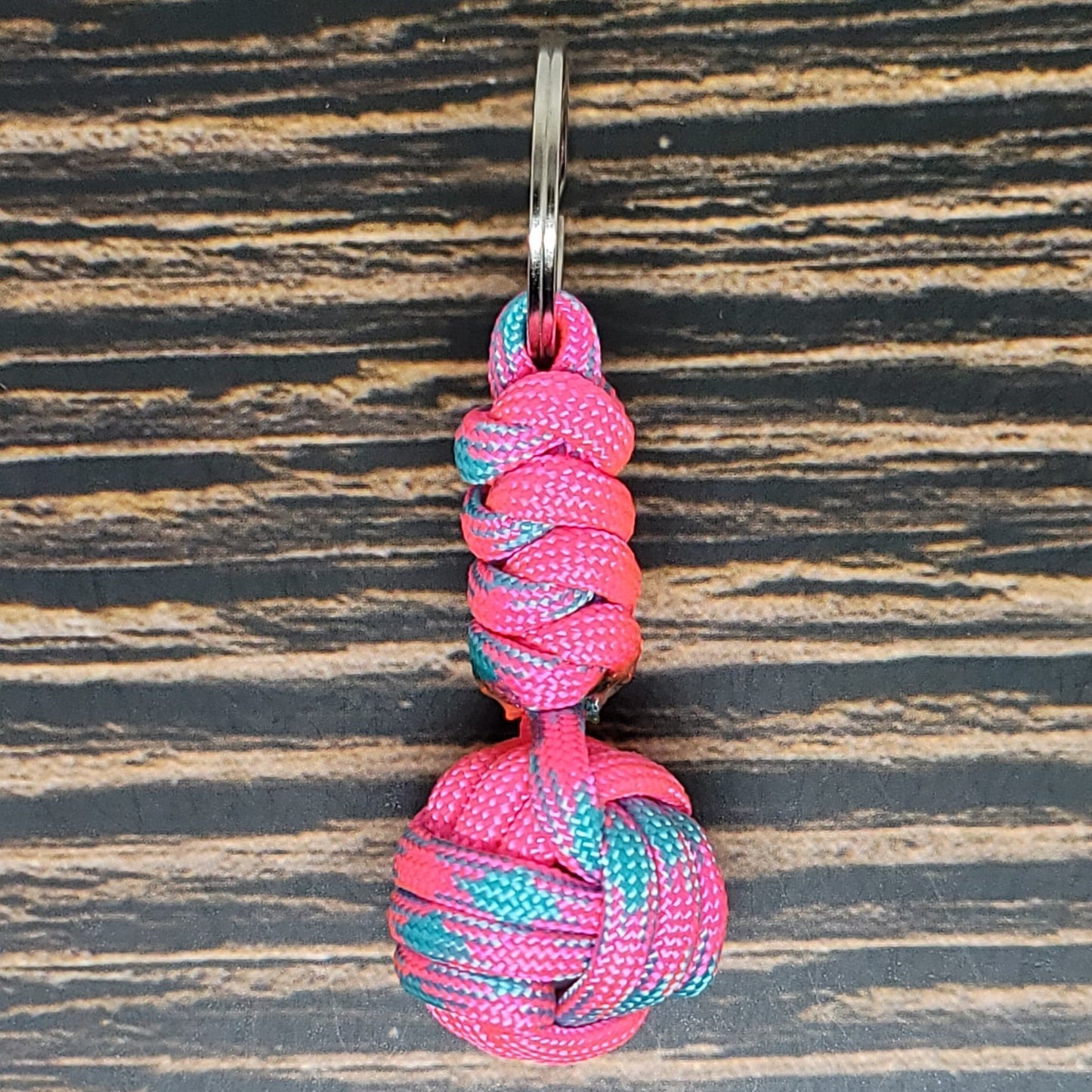 a pink and blue knoted keychain on a wooden surface