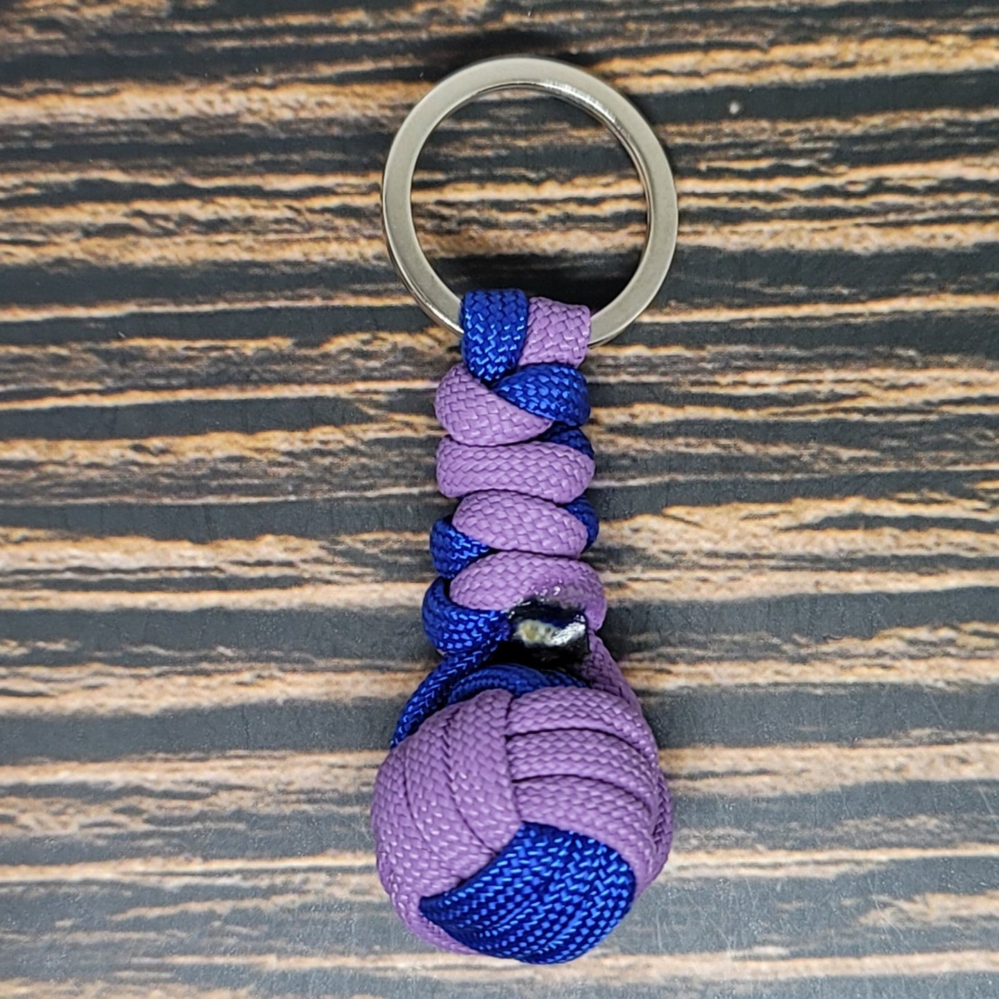 a purple and blue knoted keychain on a wooden surface