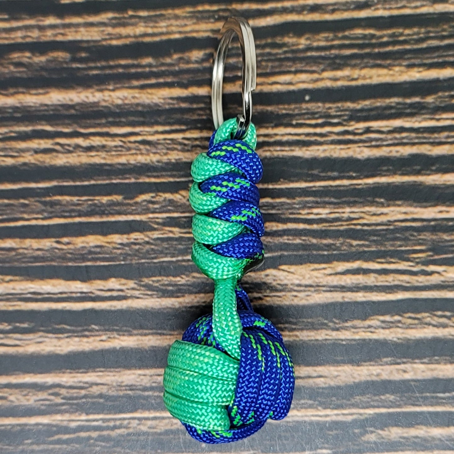 a green and blue knoted keychain on a wooden surface