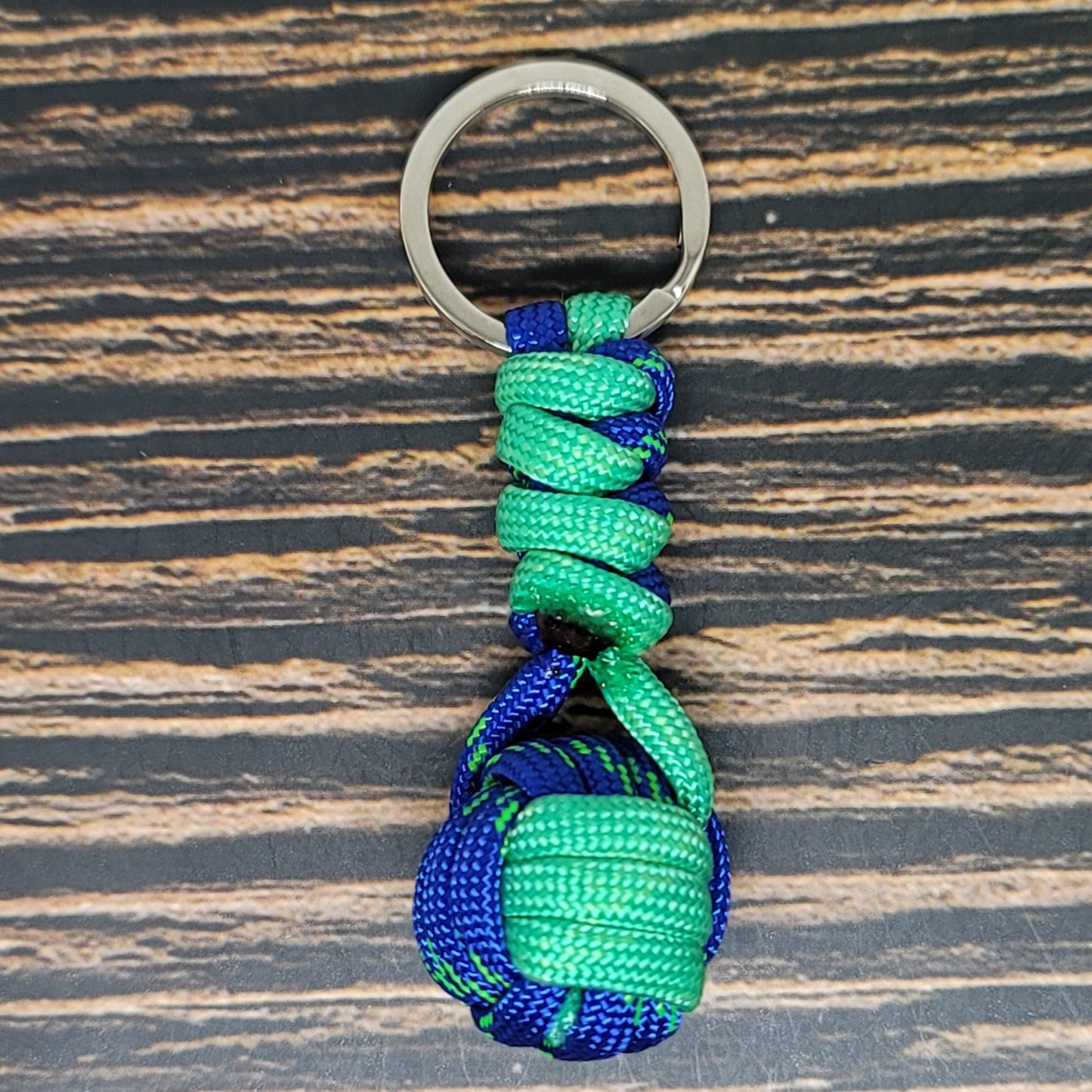 a green and blue knoted keychain on a wooden surface