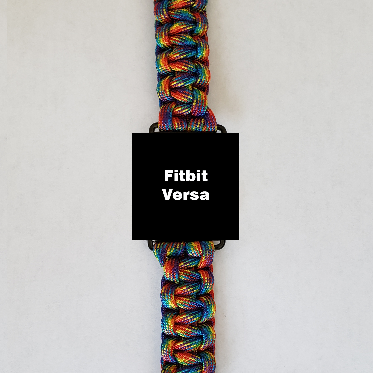 An Insanely Paracord Fitbit Versa Paracord Watch Band - Durable, Stylish, & Customizable with a vibrant, high-quality paracord band made of multicolored strands. The rainbow spectrum of the paracord watch bands stands out, while the watch face displays "Fitbit Versa" on a black background. Perfect for outdoor activities, it is set against a plain white backdrop.
