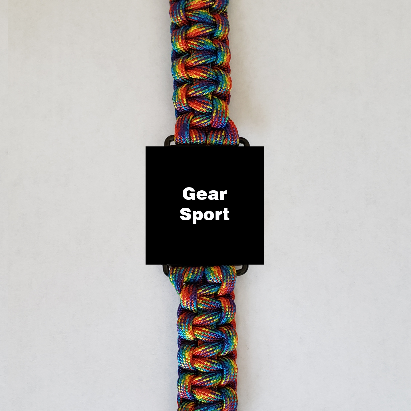 A high-quality Insanely Paracord Gear Sport Paracord Watch Band - High-Quality, Durable, and Stylish Smartwatch Accessory with a black rectangular element in the middle displaying "Gear Sport" in white. The tightly woven paracord features vibrant hues of blue, green, yellow, red, and orange, making it perfect for outdoor enthusiasts. The background is plain white.