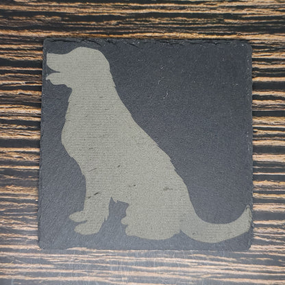 A Custom Slate 4" Coaster - Personalized Laser Engraved Drink Coaster by Insanely Paracord with a silhouette of a sitting dog laser engraved on it. The dog is facing left with its mouth slightly open. The textured surface of the coaster complements the wooden table's visible grain patterns, making it an ideal corporate gift.