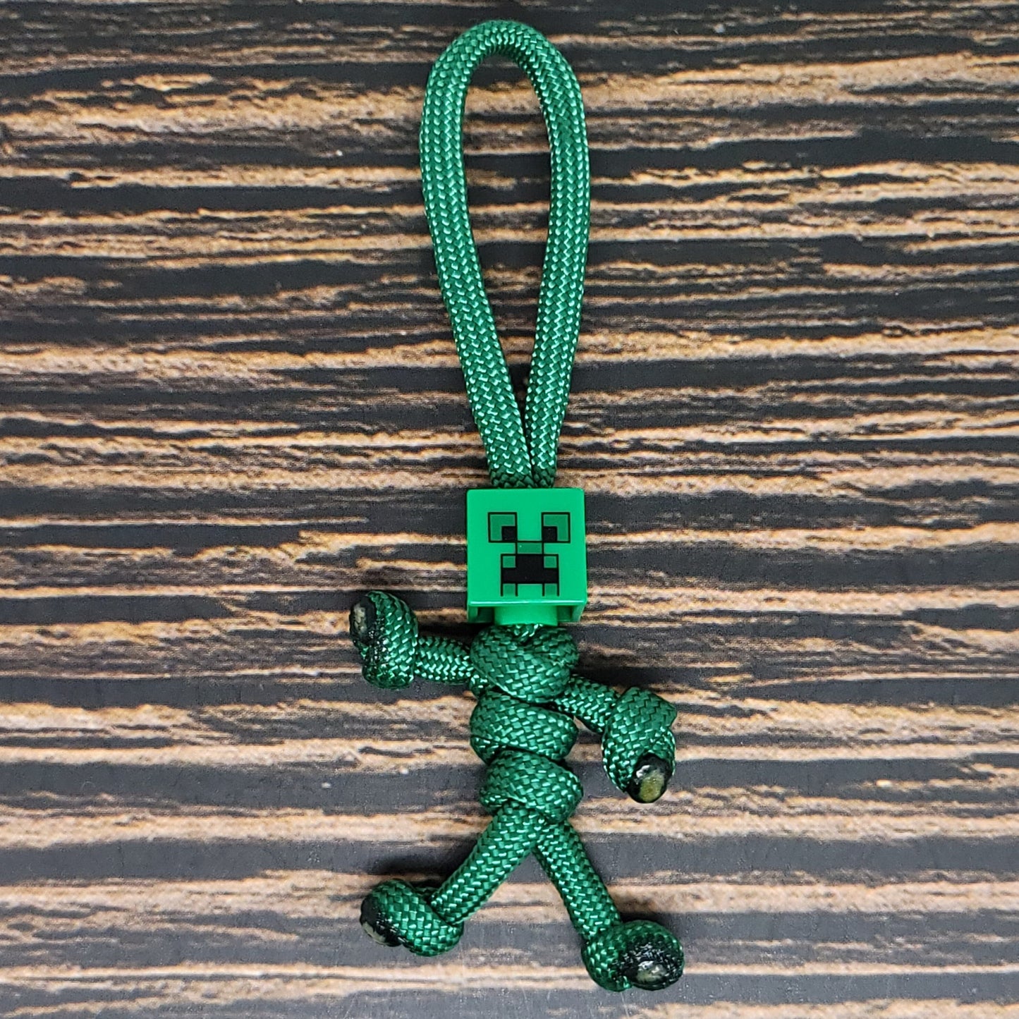 a green keychain with a small robot on it