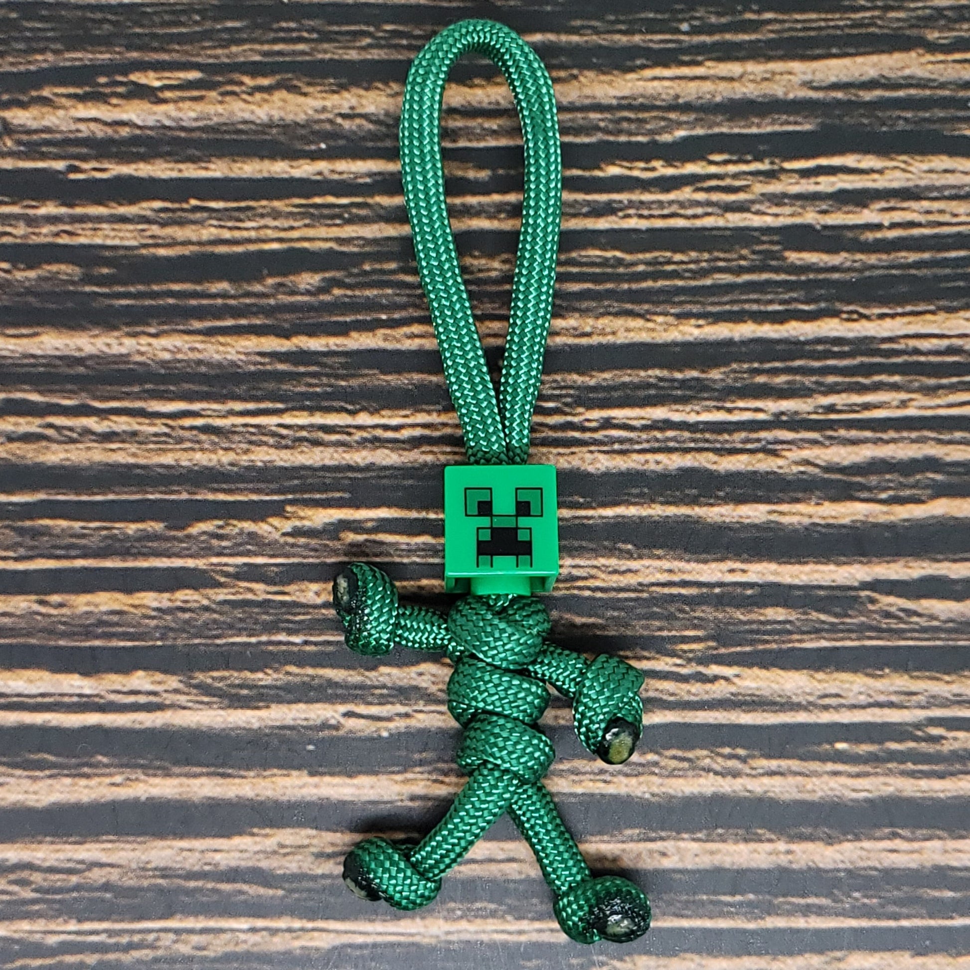 a green keychain with a small robot on it