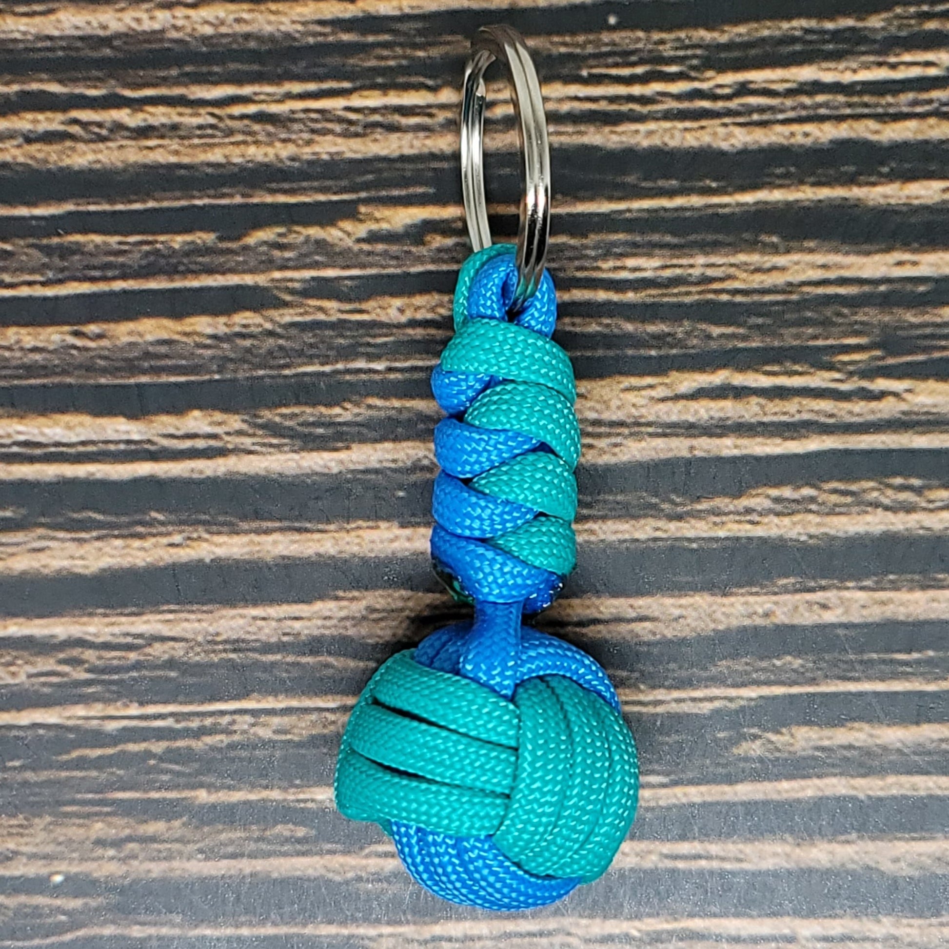 a blue and green knoted keychain on a wooden surface
