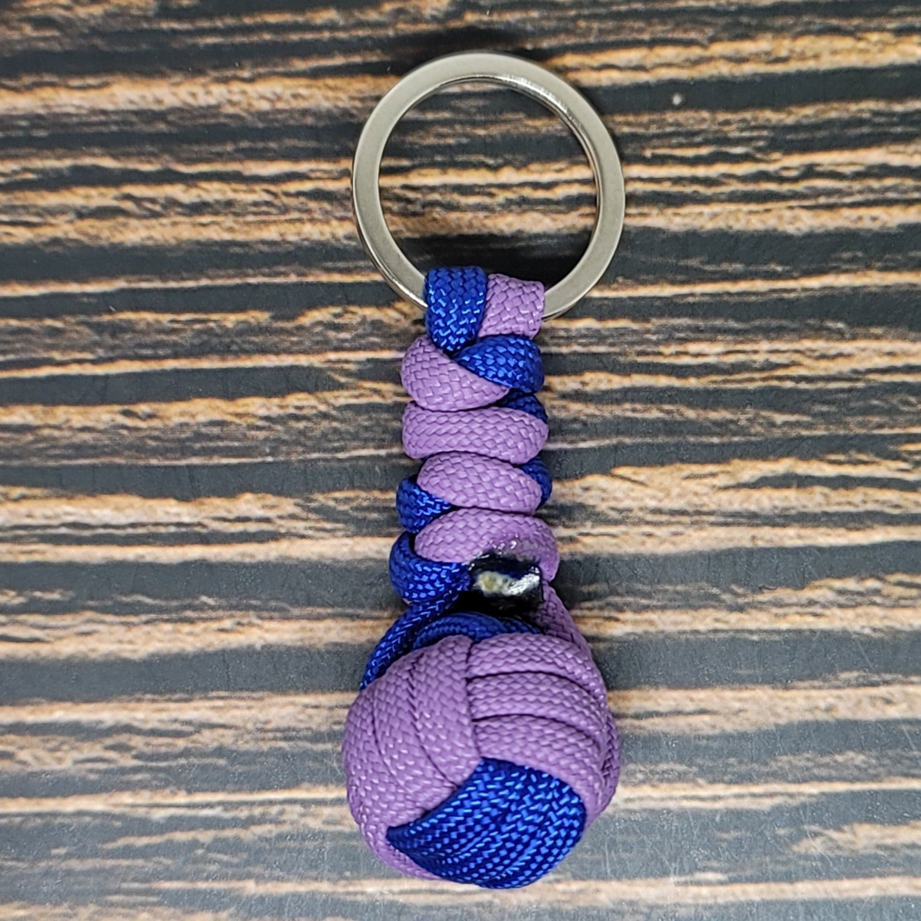a purple and blue knoted keychain on a wooden surface