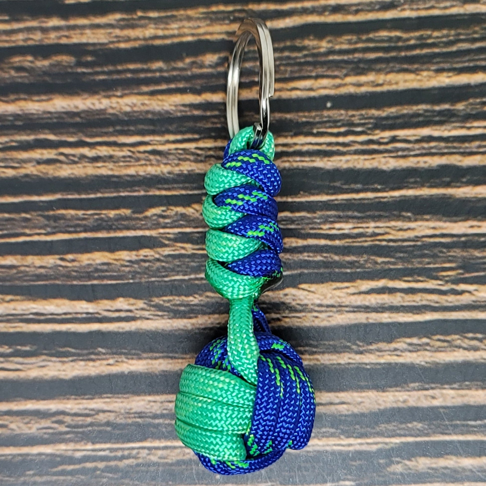 a green and blue knoted keychain on a wooden surface