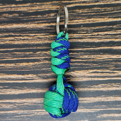 a green and blue knoted keychain on a wooden surface