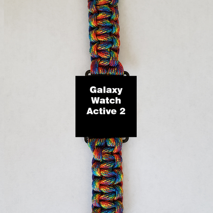 An Insanely Paracord Galaxy Watch Active 2 with a vibrant rainbow-colored paracord watch band - durable, stylish, & versatile, perfect for outdoor enthusiasts, is displayed against a plain white background. The watch face is black and features the text "Galaxy Watch Active 2" in white.